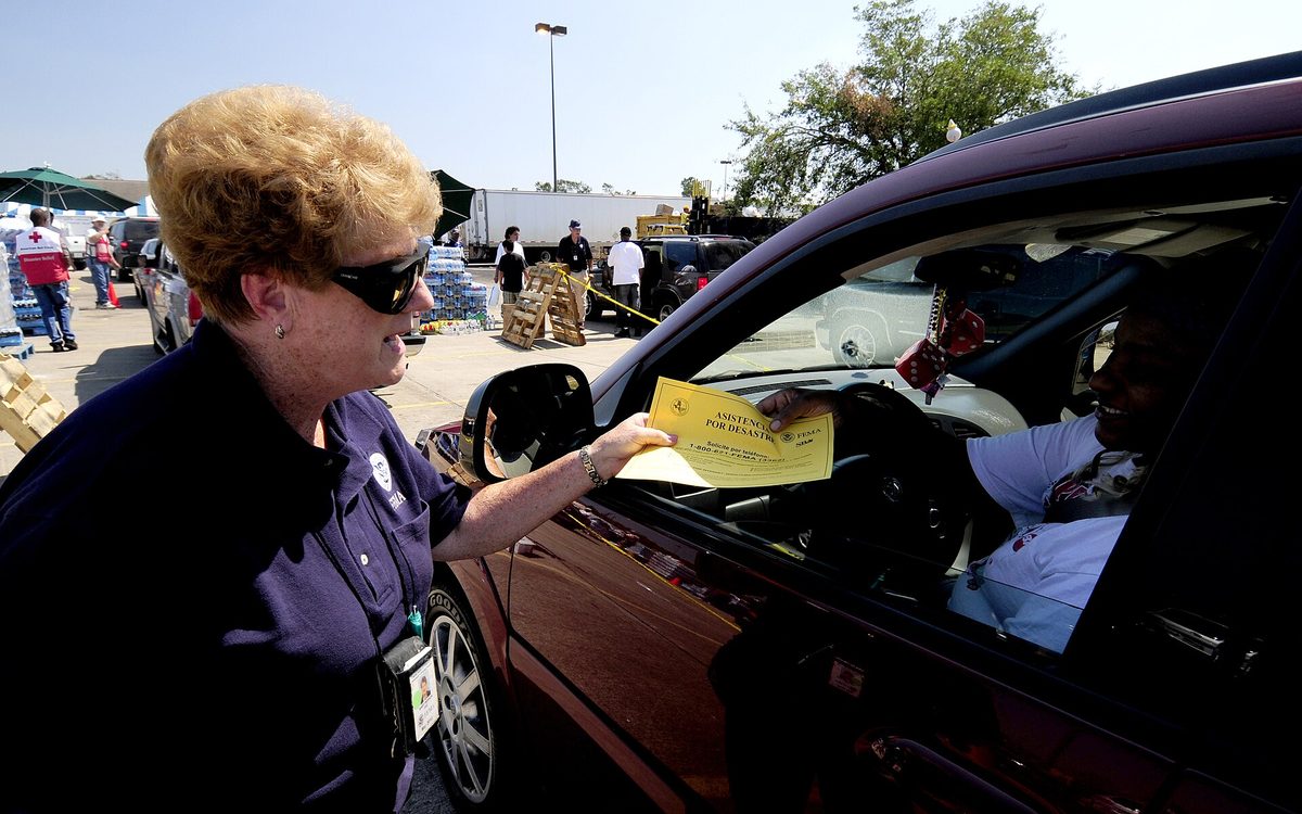Baytown, TX, September 28, 2008 -- Community Relations (CR) specialist Mary Peirson handing a FEMA flier to a resident at a commodity Point of Distribution (POD). Hundreds of residents will utilize this POD today and CR will get important FEMA recovery information to community members that need it. Mike Moore/FEMA