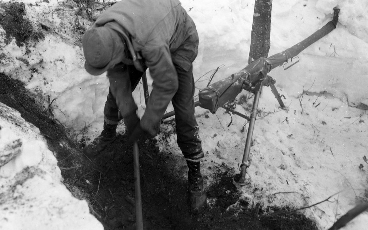 SC 364478 - Pvt. Sam Zimmerman, Goose Creek, Texas, S.V. Bat., 12th F.A. digging emplacement in 2' of snow along road to halt infantry - .50 caliber air-cooled 